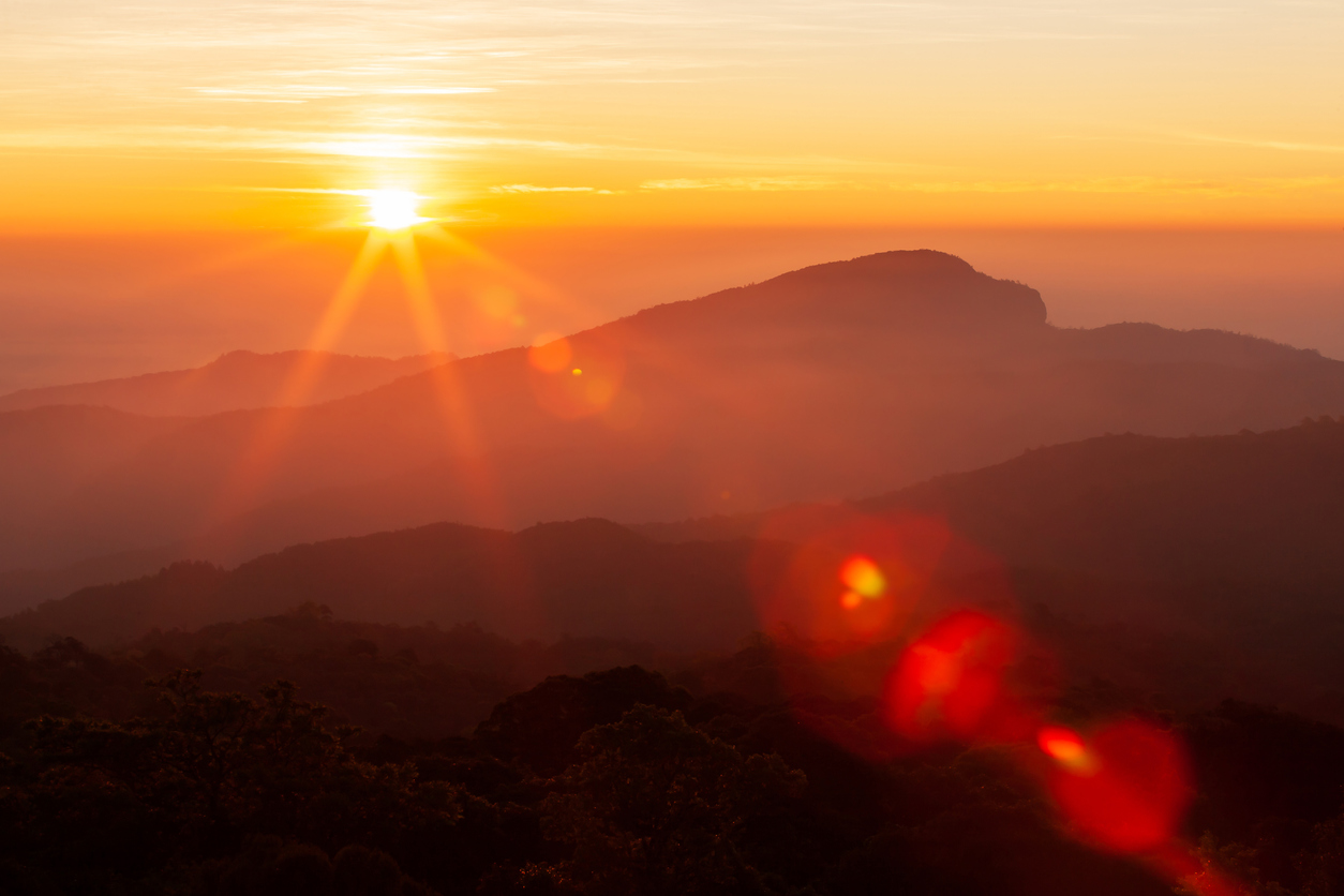 The sun rising over mountains on a winter day.